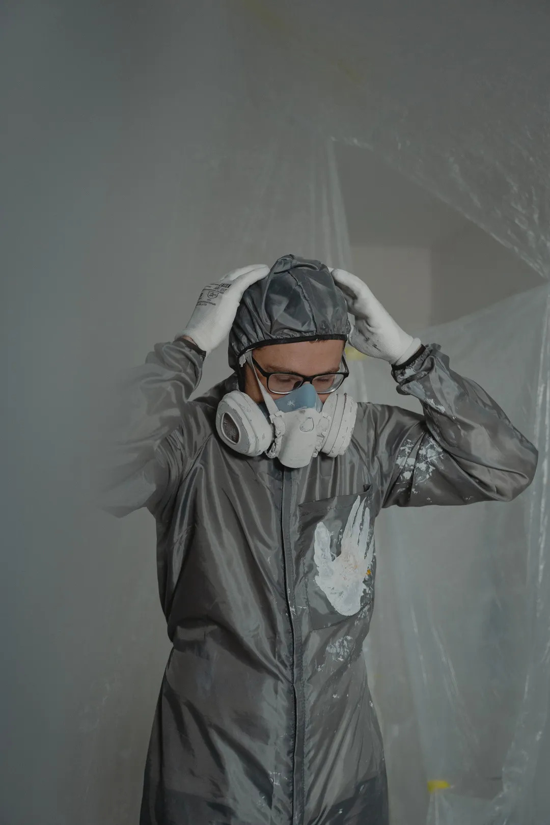 Worker in coveralls and a respirator inside plastic containment sheeting